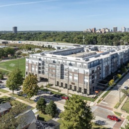 exterior of building with green turf and some seating